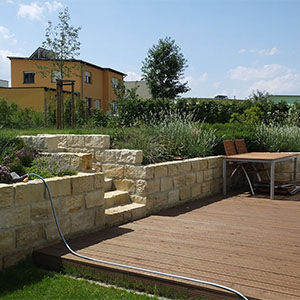 Natursteinmaterialien in warmen Farbtönen prägen diesen Garten